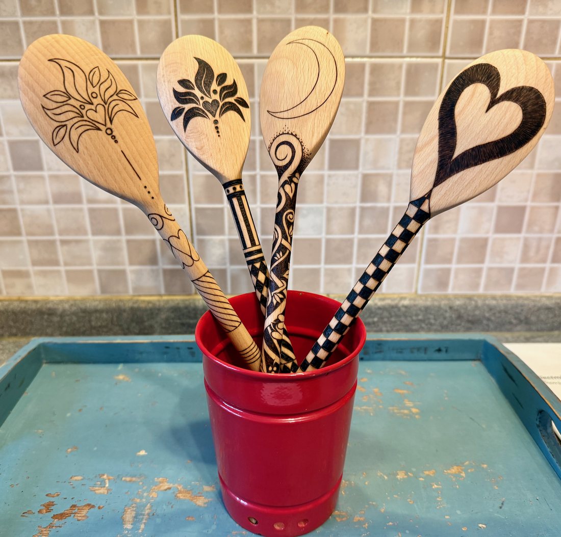 Pyrography spoons standing in a red pot in a kitchen