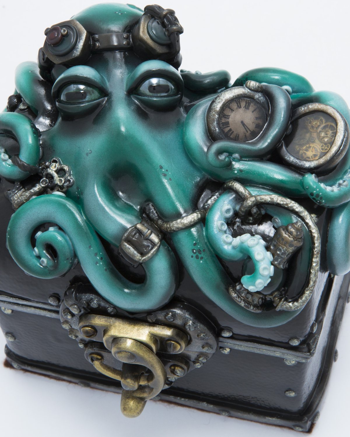Sculpted teal octopus wearing goggles across the lid of a black chest, tentacles wrapped around a clock face and gears
