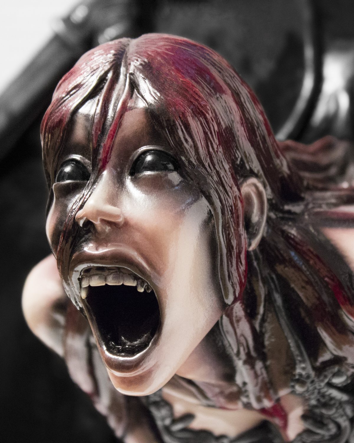 Close up of a screaming gothic figure sculpture with red streaked hair, mounted on a black diamond plaque