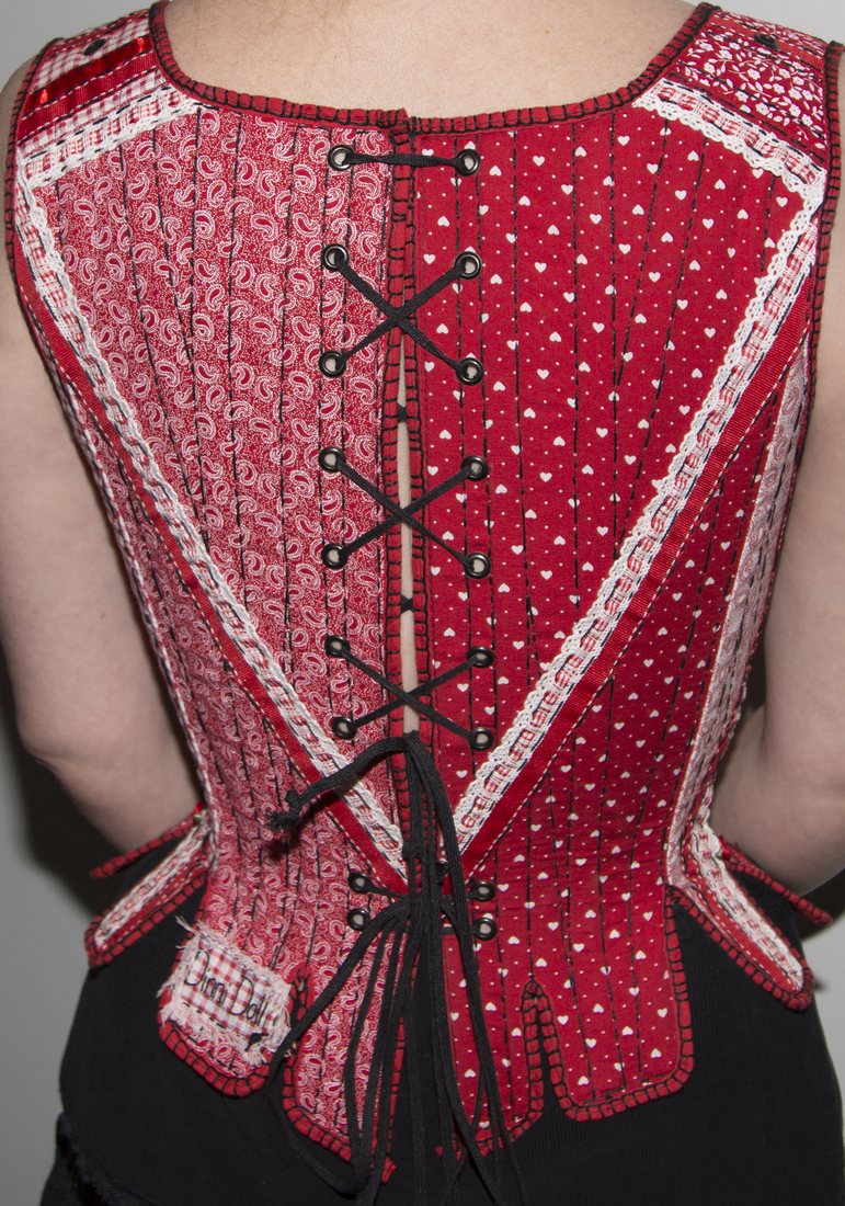 Back view of a red handmade corset showing the lacing
