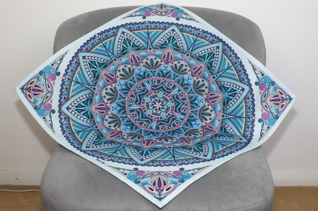 Hearty Mandala printed cotton tea towel draped over a grey chair